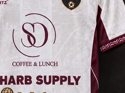 Close-up van een wit shirt met gesublimeerd patroon en sponsorbedrukking